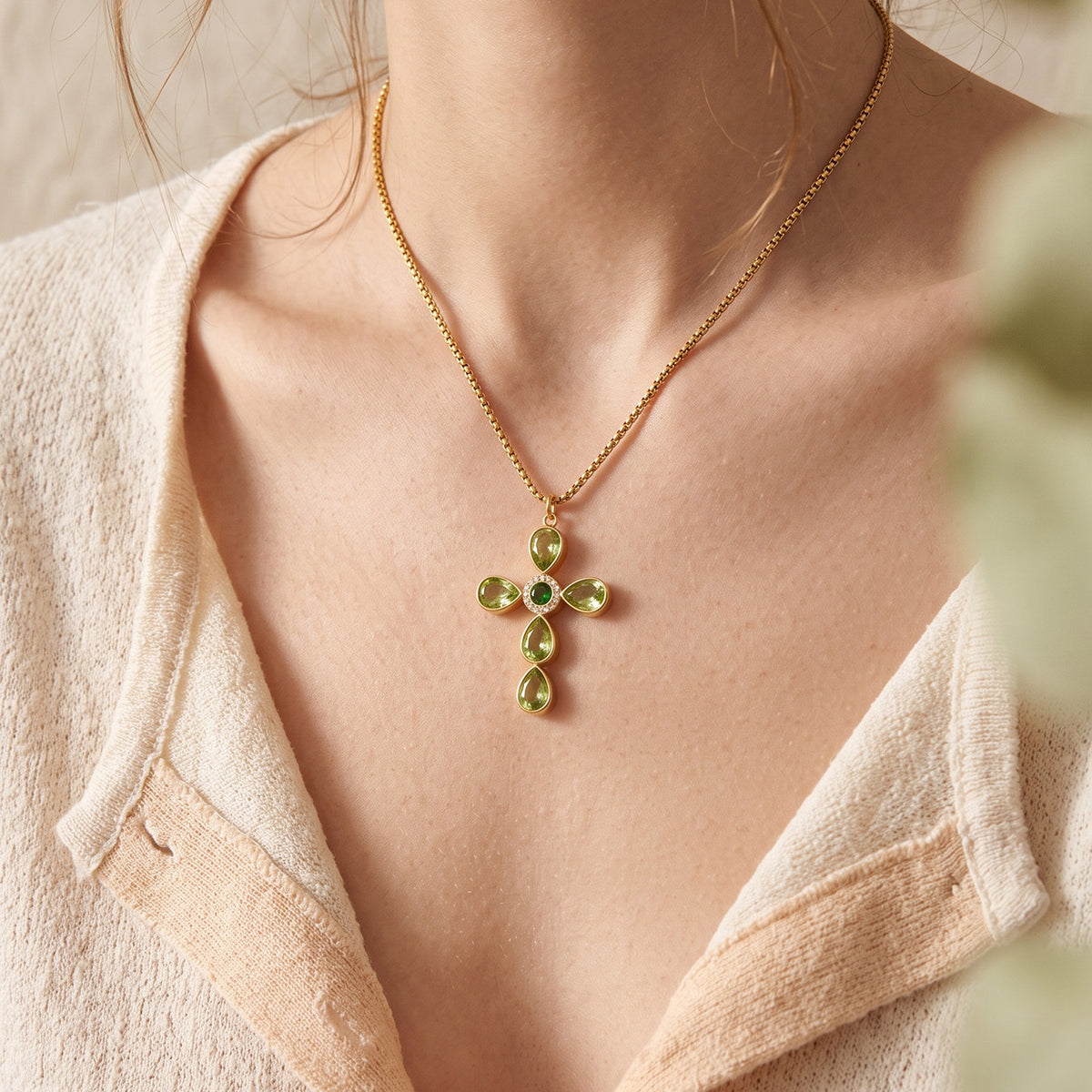 Green faceted stone cross pendant necklace worn at the collarbone