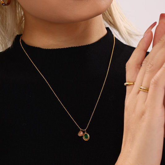 Model wearing a single green oval zircon pendant necklace with a black top