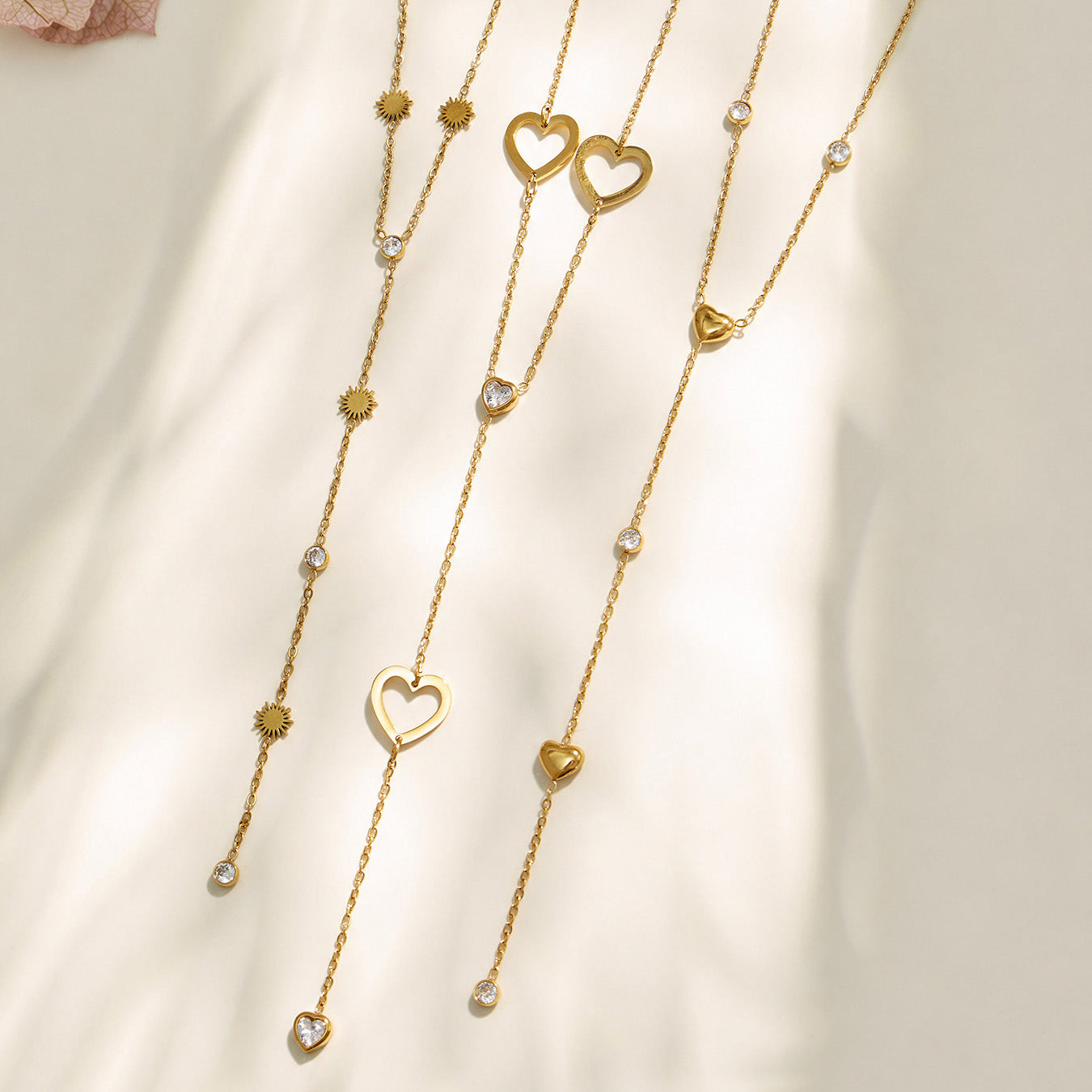 Gold heart, floral and butterfly Y necklaces displayed in a vertical assortment