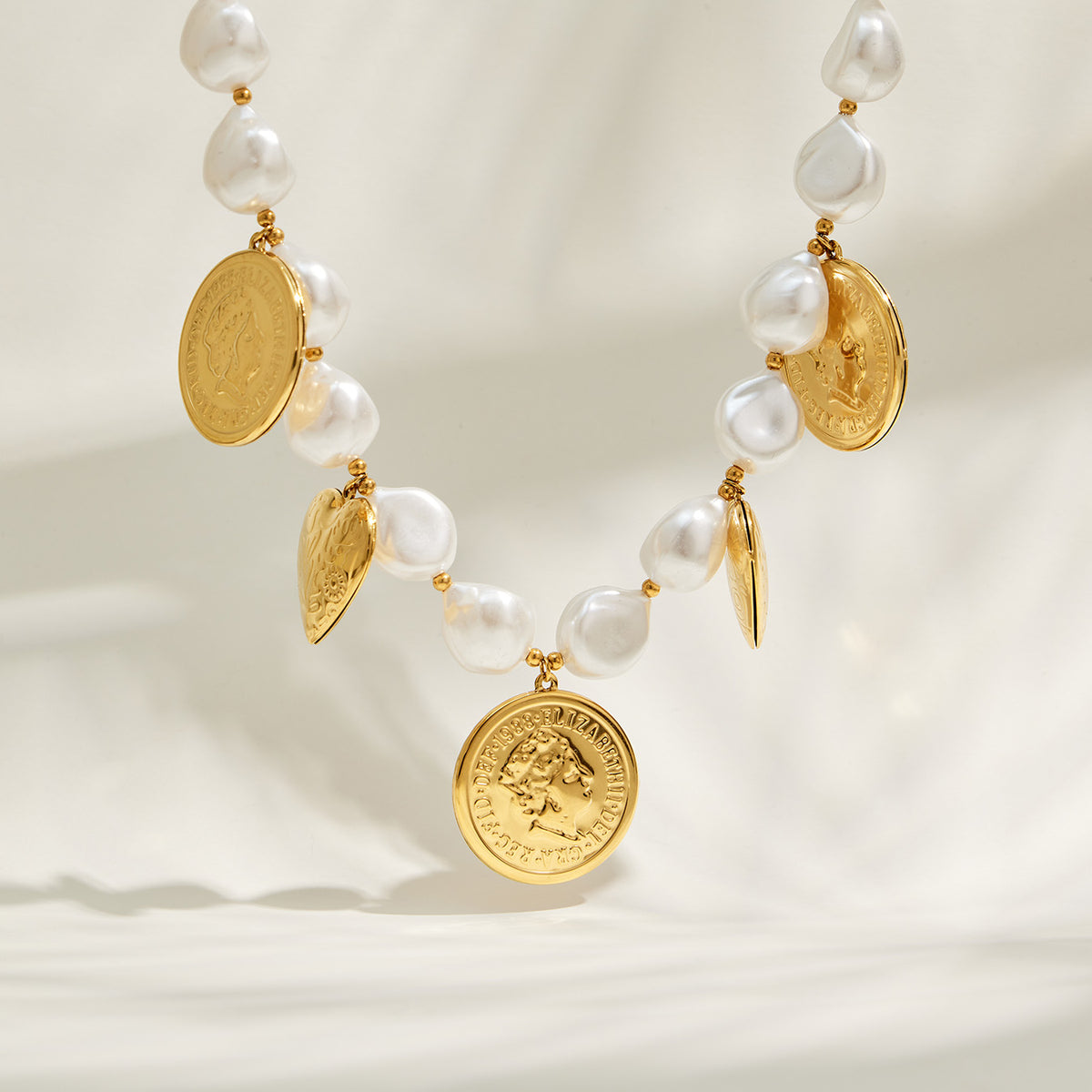 Ivory bead heart charm necklace with gold medallion pendants on display