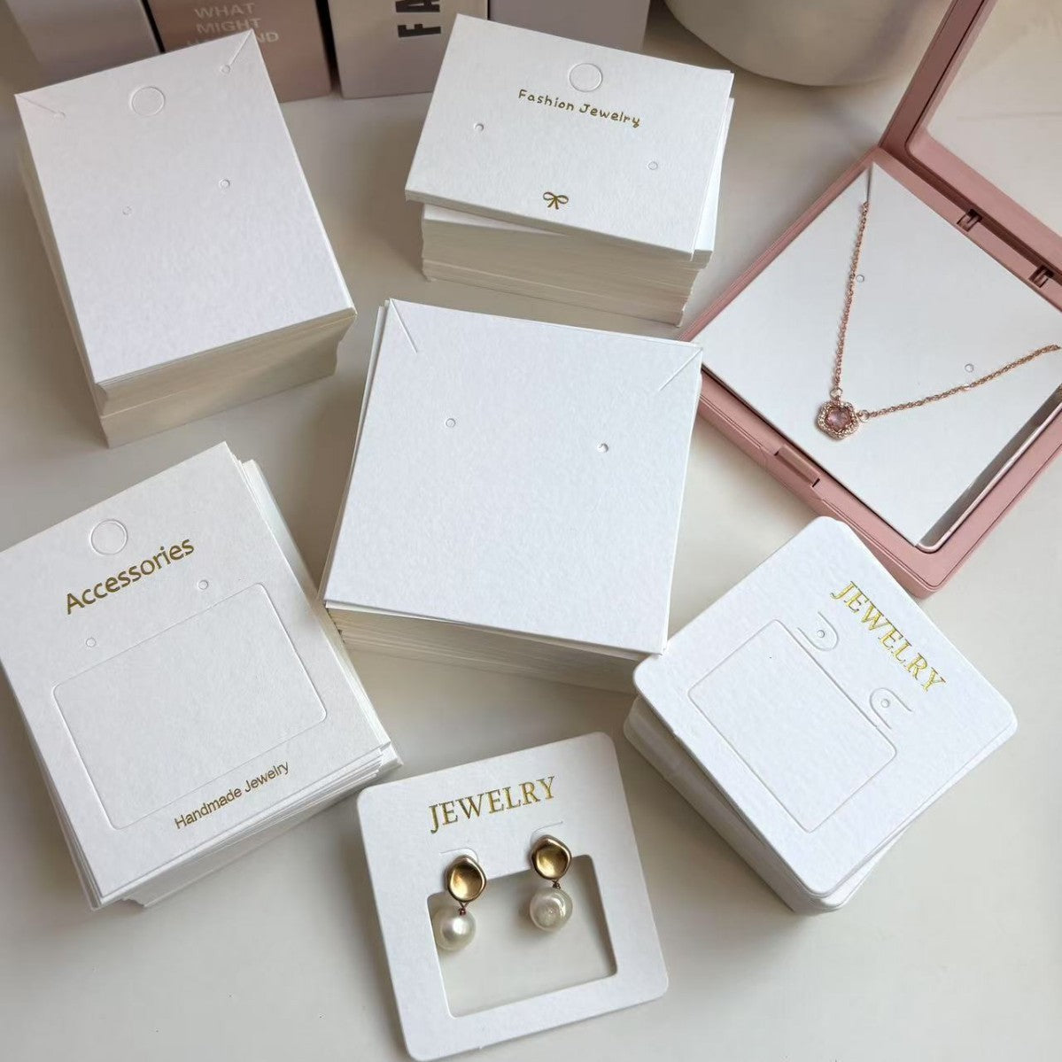 White jewelry display cards arranged with necklace and earring packaging boxes