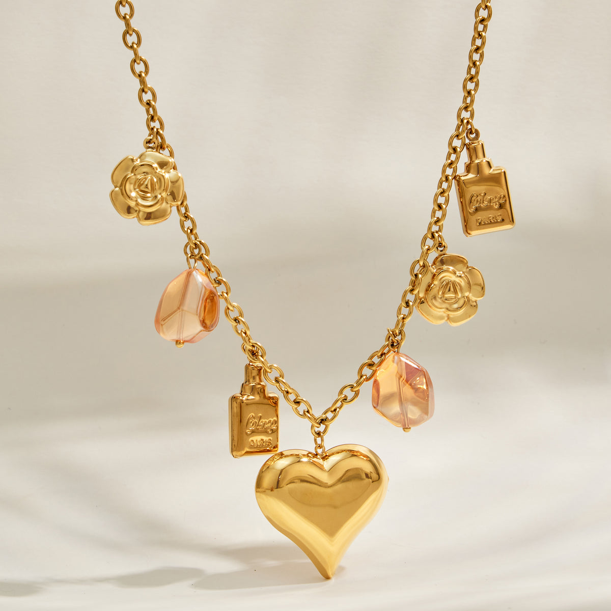 Large gold heart pendant with resin and decorative charms on stainless steel chain