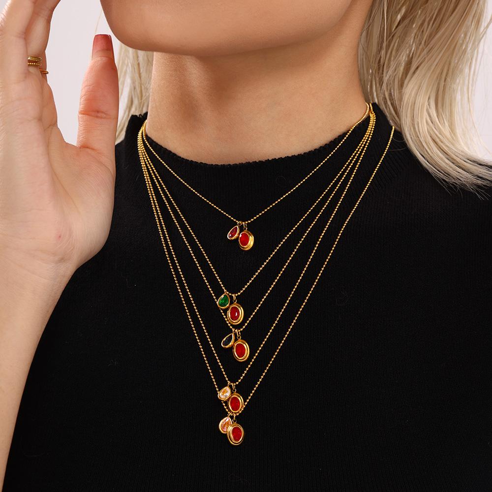 Model styling layered colorful zircon drop necklaces with red and green stones