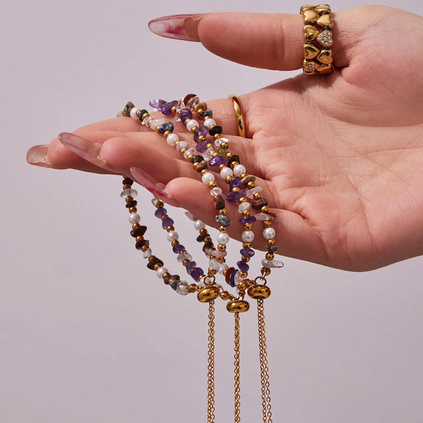 Multiple natural stone and pearl bracelets displayed across a model hand