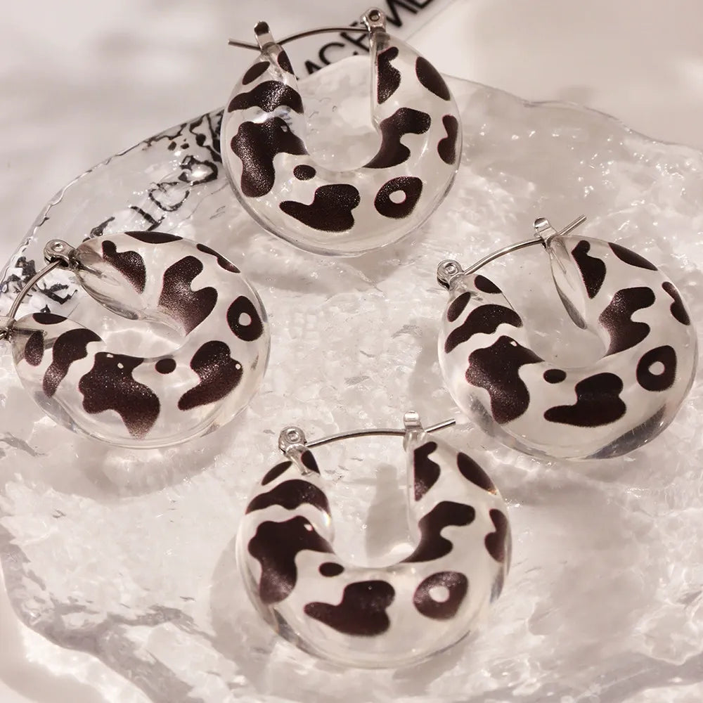 Multiple pairs of black and white leopard print resin hoop earrings arranged in a product display