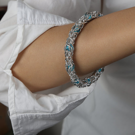 Men’s blue accent Byzantine chain bracelet worn on wrist, made with stainless steel for street-style jewelry buyers