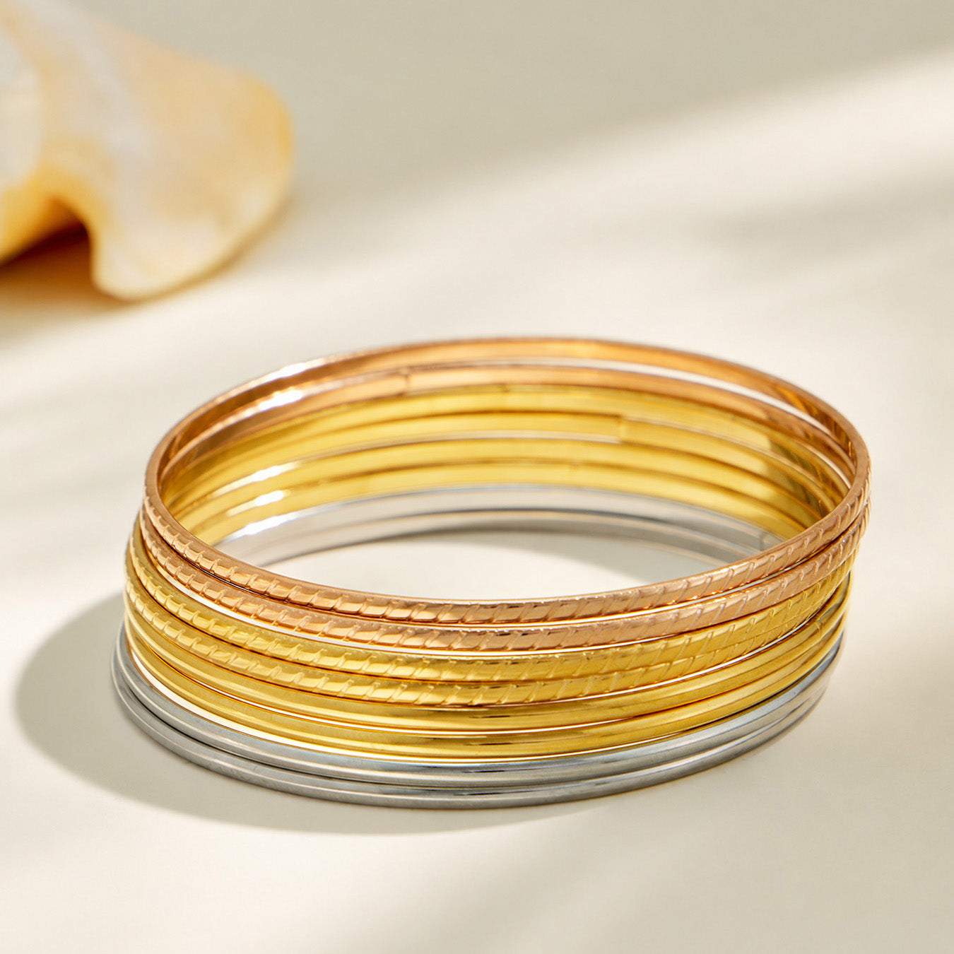 Stacked display of slim steel, gold and rose gold-tone stainless steel bangles