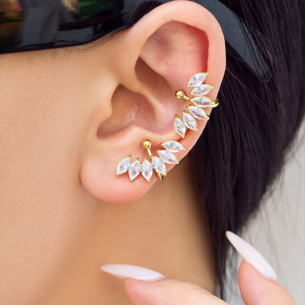 Side view of a model wearing a gold leaf-inspired ear cuff with sparkling clear stones and a curved design