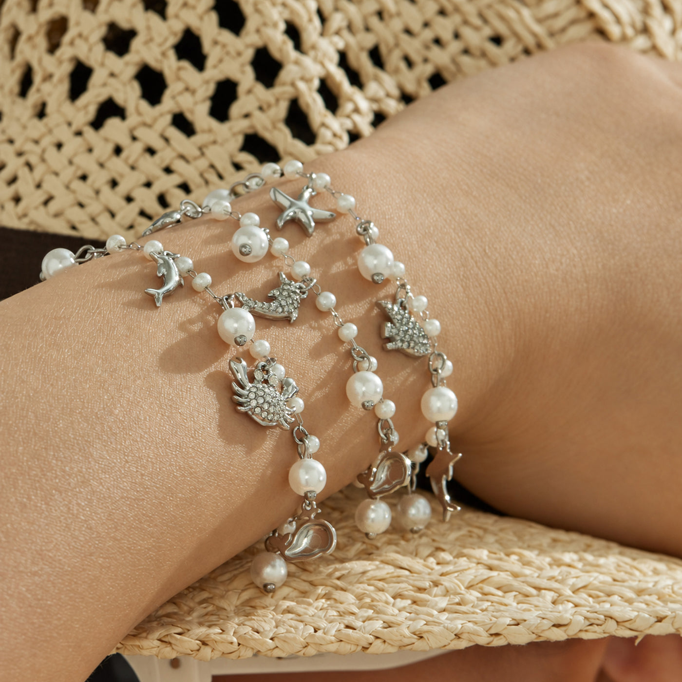 Steel finish ocean charm pearl bracelets layered on a model wrist with marine-inspired charms