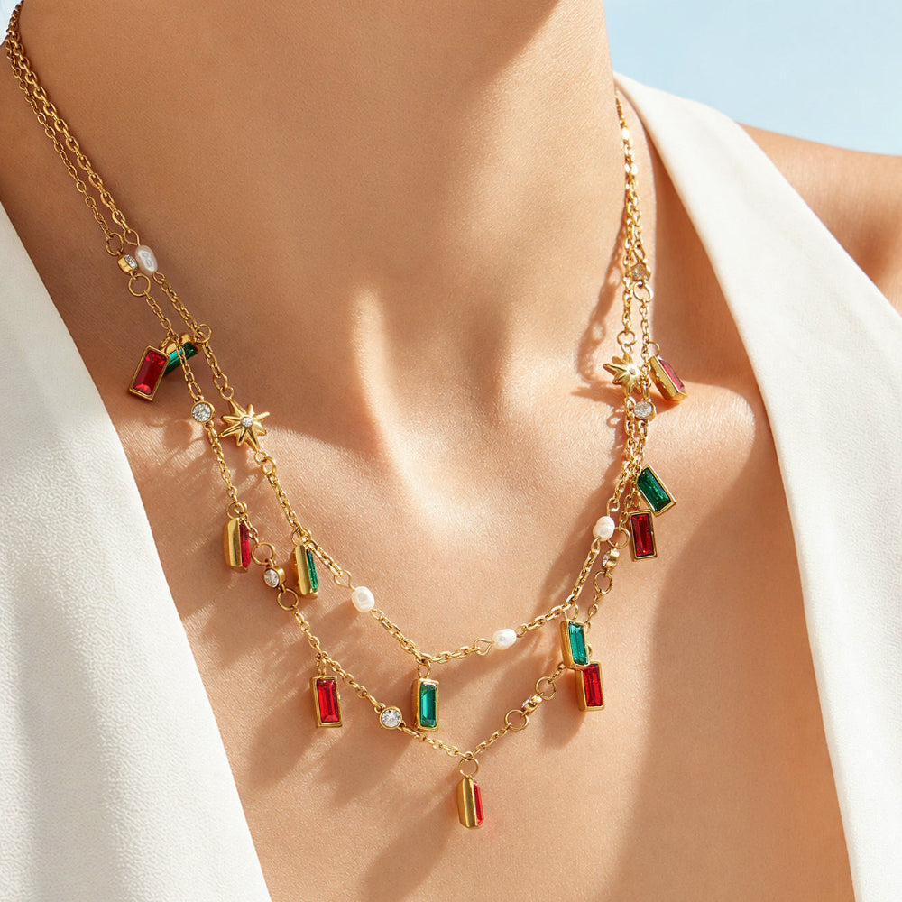 Close up of colorful glass stone charm necklace worn on neckline with gold tone chain and pendant details