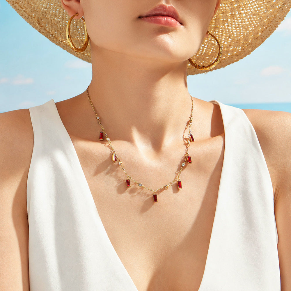 Model close up wearing colorful glass stone necklace with vacation-ready gold charm design