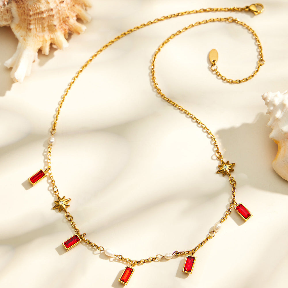 Red glass stone charm necklace with gold tone chain and pearl-style accents for gift jewelry collections