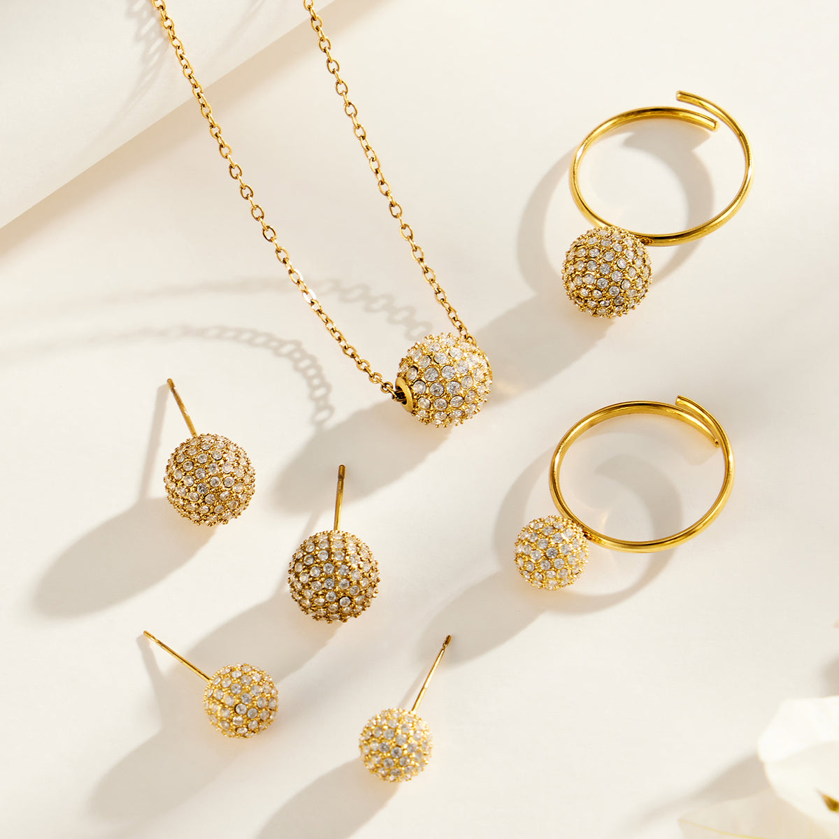 Pavé zircon ball necklace, earrings and open rings displayed as a matching jewelry collection