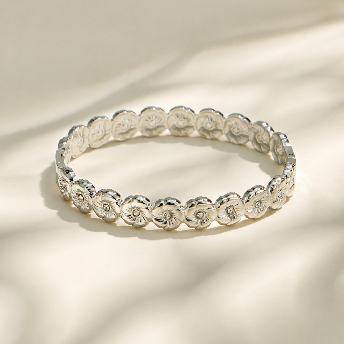 Polished steel floral cubic zirconia hinged bangle on a light background