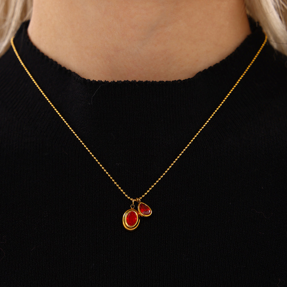 Model wearing a red double zircon drop necklace with a black top