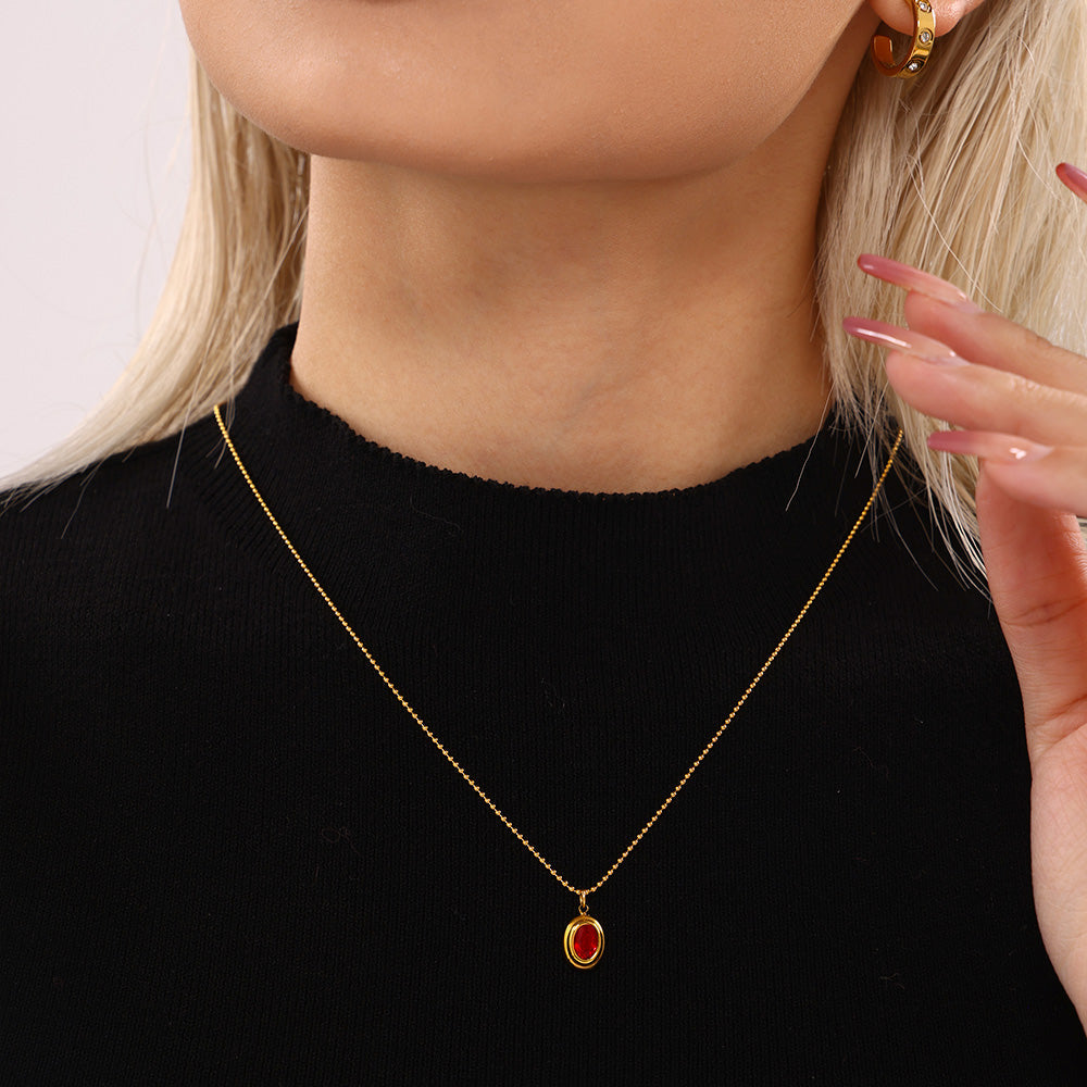 Model wearing a single red oval zircon pendant necklace with a black top