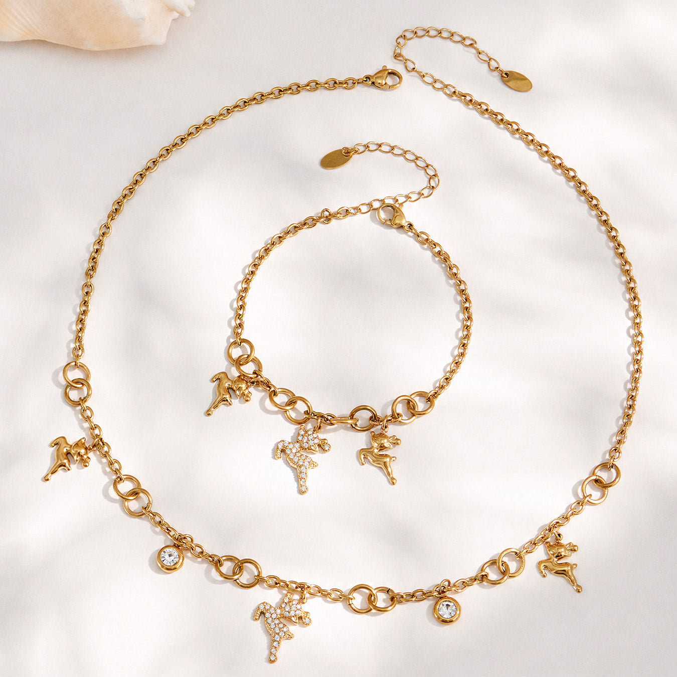 Gold reindeer necklace and bracelet arranged together in a circular flat lay