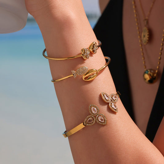 Model wearing layered gold 5A zircon open bangles including rose and bee designs