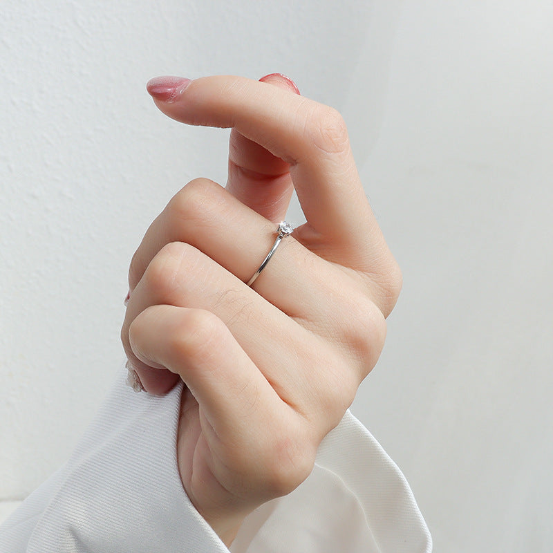 Silver tone minimalist solitaire stacking ring with small round clear stone worn on hand