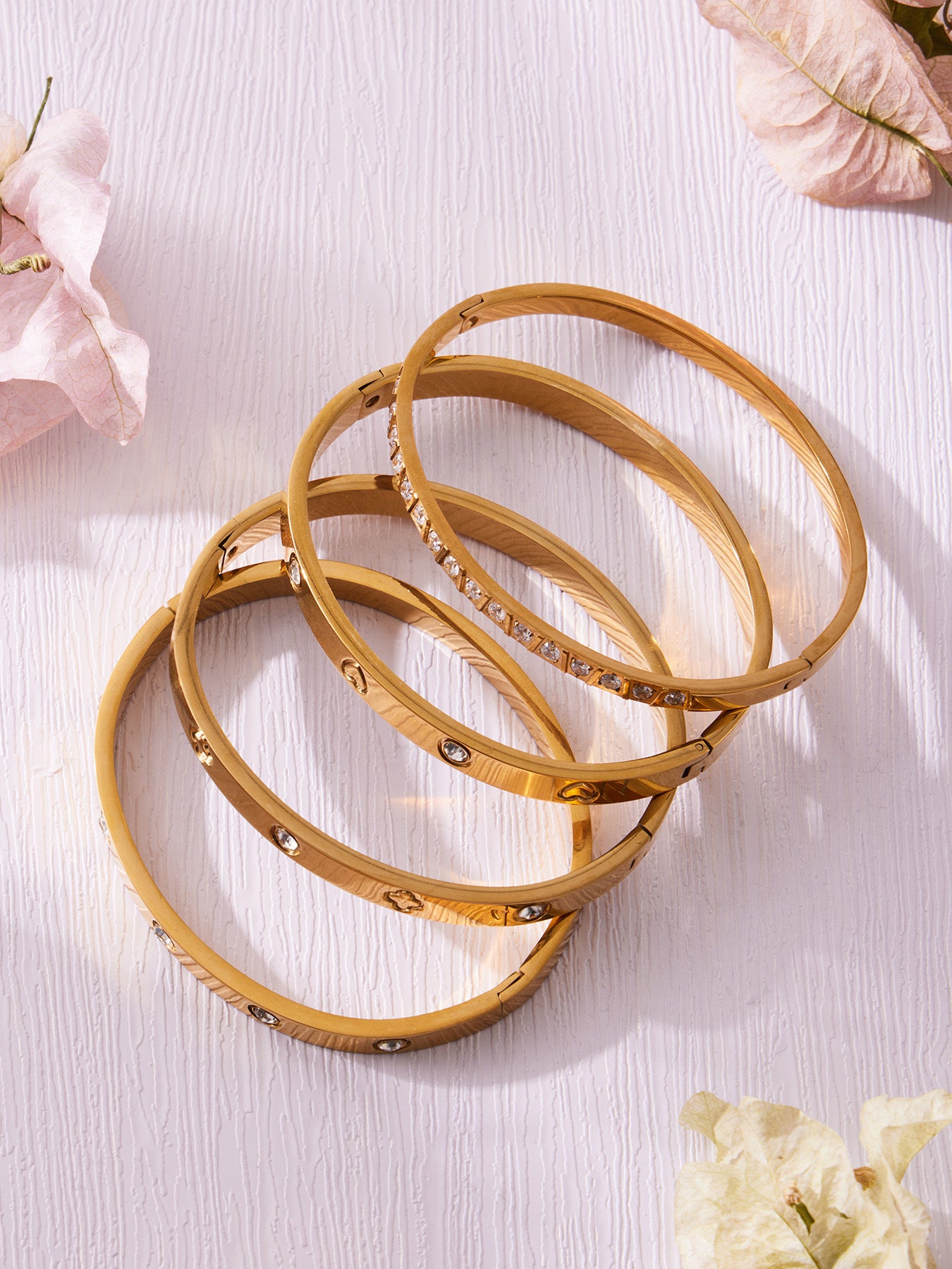 Slim gold stackable bangles arranged in an overlapping flat lay