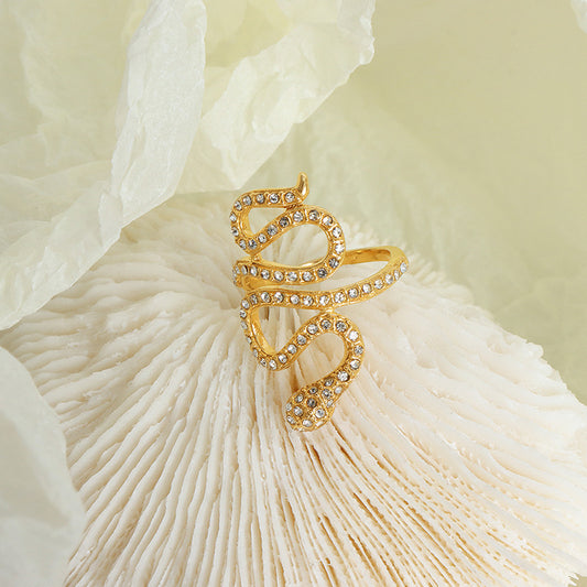 Gold snake open ring with clear cubic zirconia in a styled flat lay