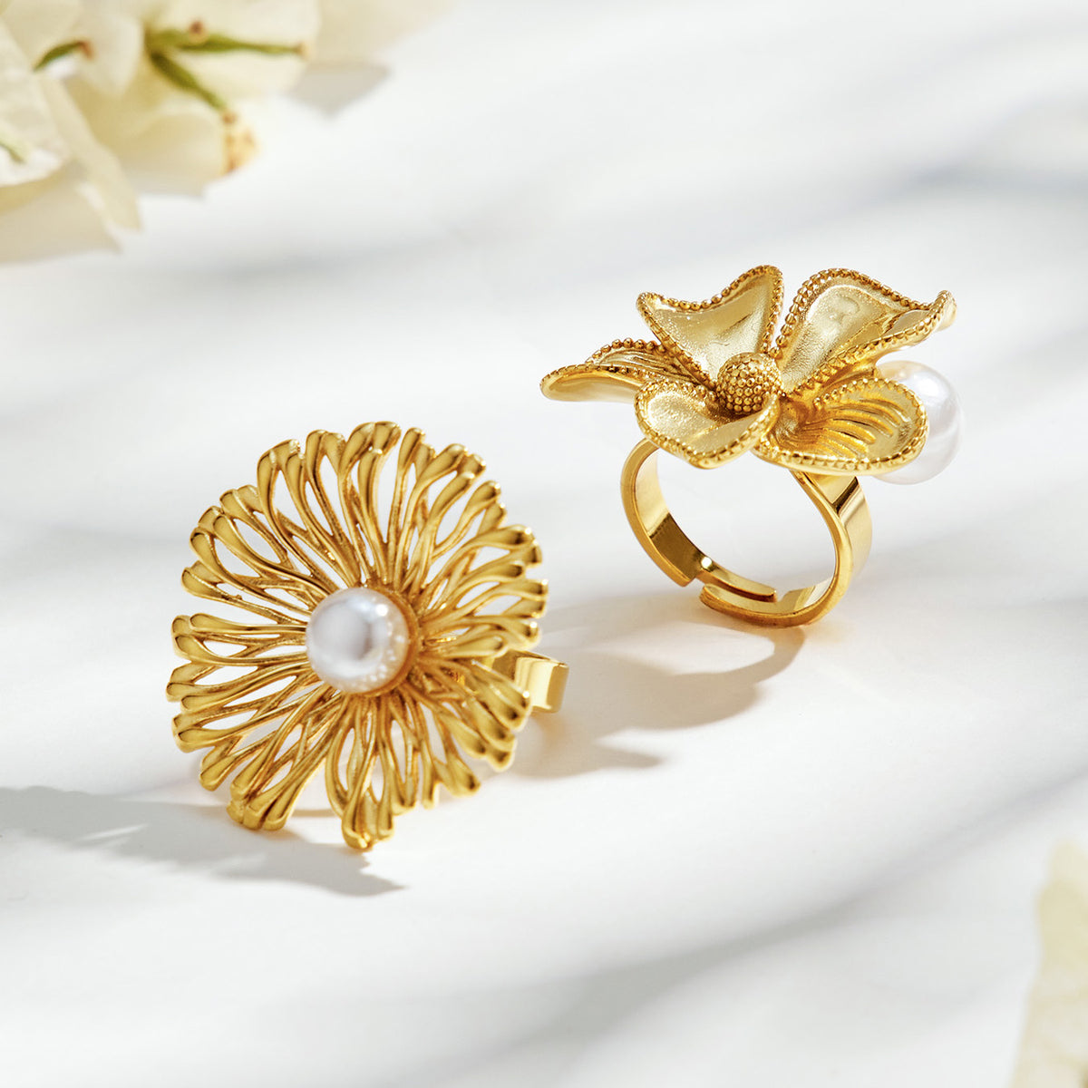 Gold-tone stainless steel openwork and sculpted flower rings with white faux pearls in natural light