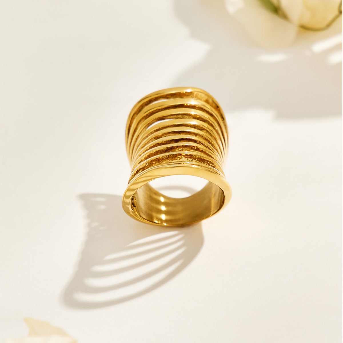 Back view of a gold-tone stainless steel multi-band ring showing the circular finger opening and layered structure
