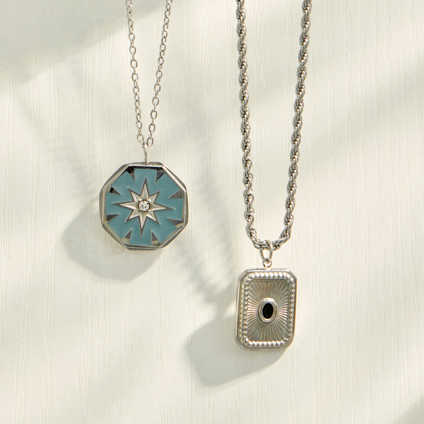 Starburst medallion and square pendant necklaces displayed on a dark background
