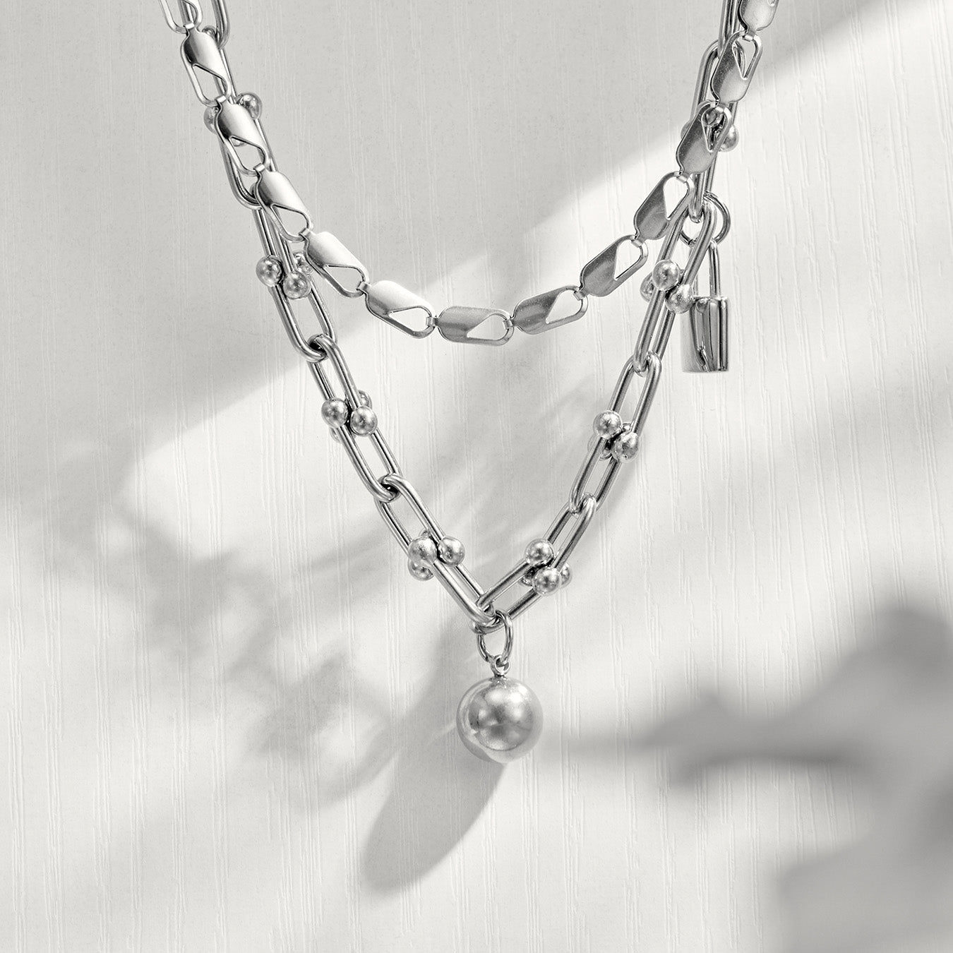 Model wearing a polished steel ball lock chain link necklace in a layered jewelry look