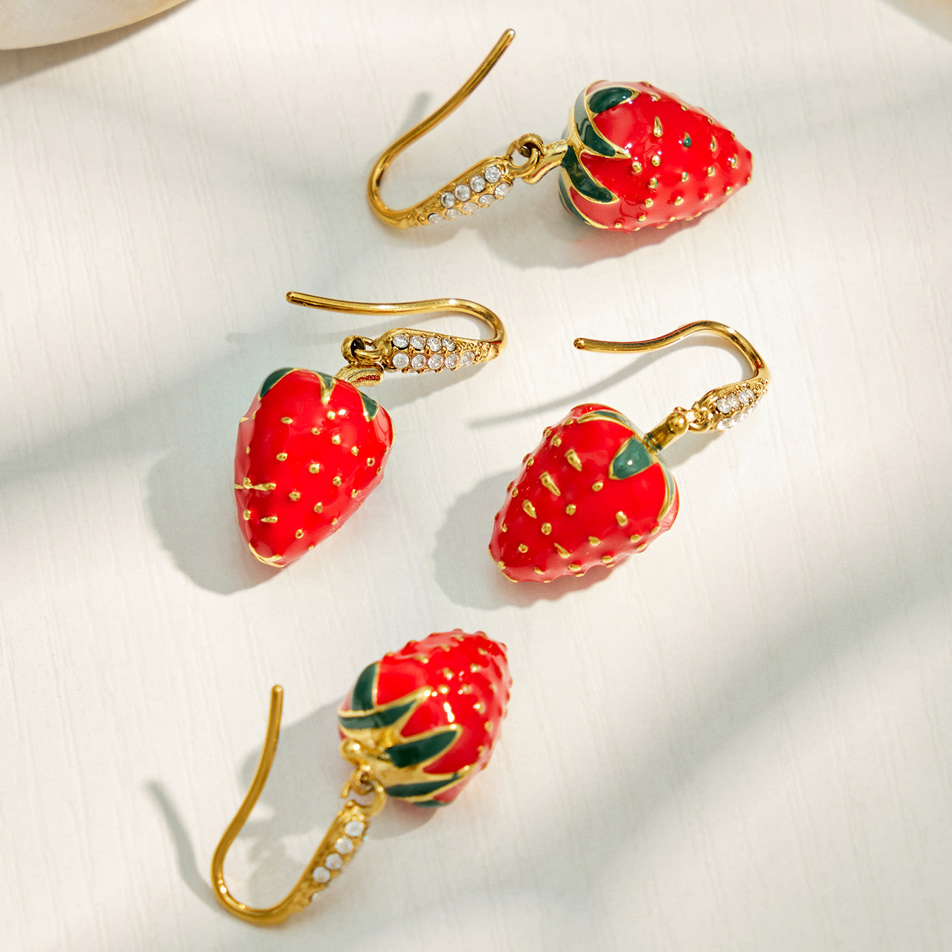 Red strawberry cubic zirconia drop earrings displayed on a light background