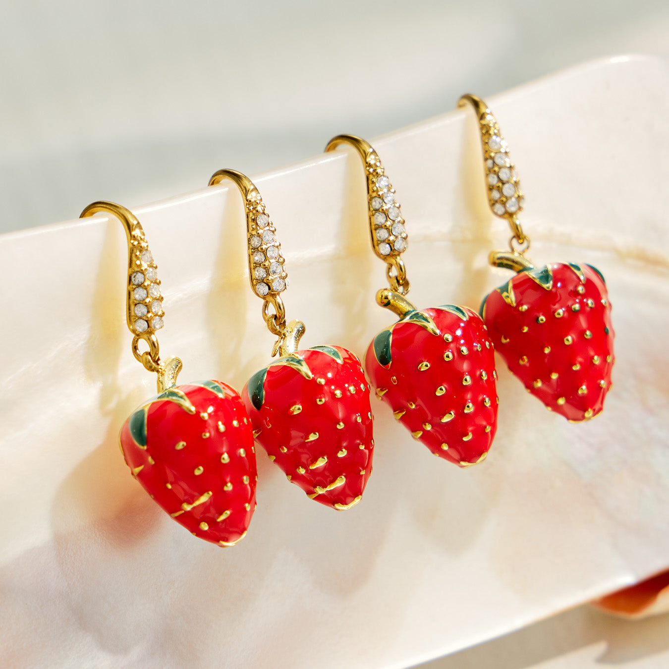Multiple pairs of red strawberry drop earrings with gold-tone details