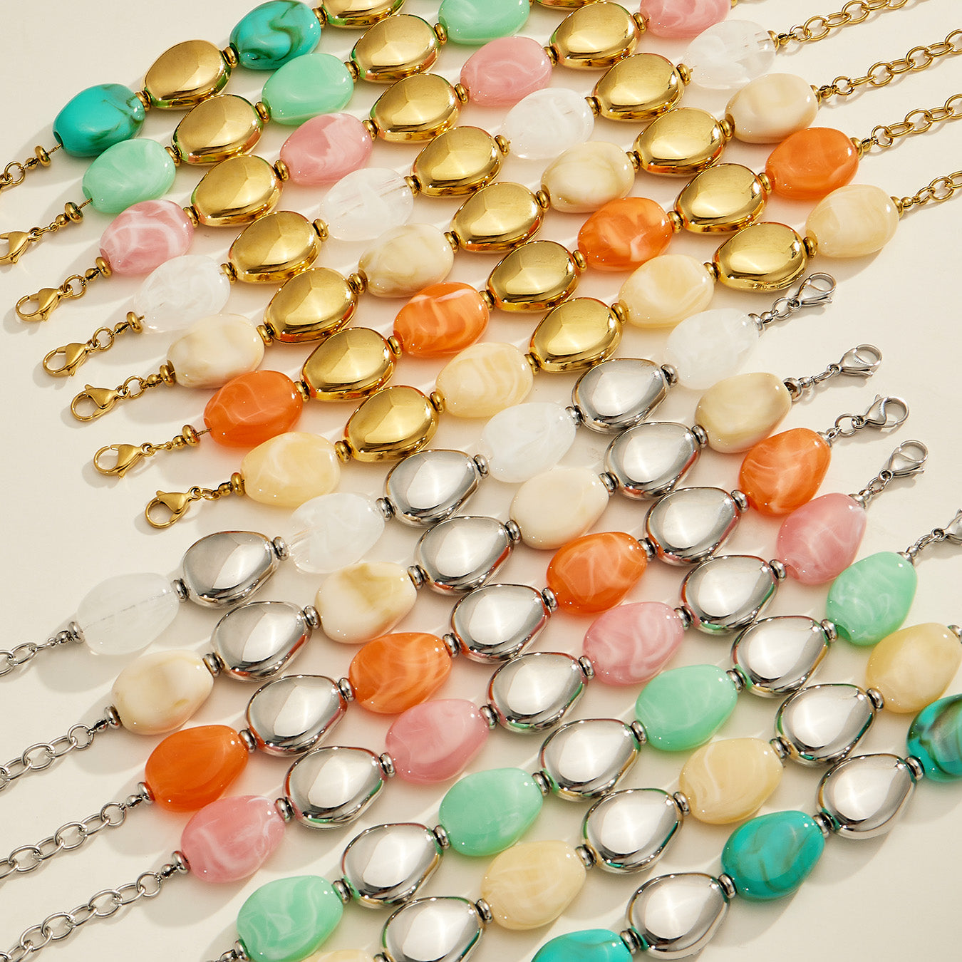 Colorful oval resin bead bracelets arranged in rows showing gold-tone and steel-tone finishes and extension chains