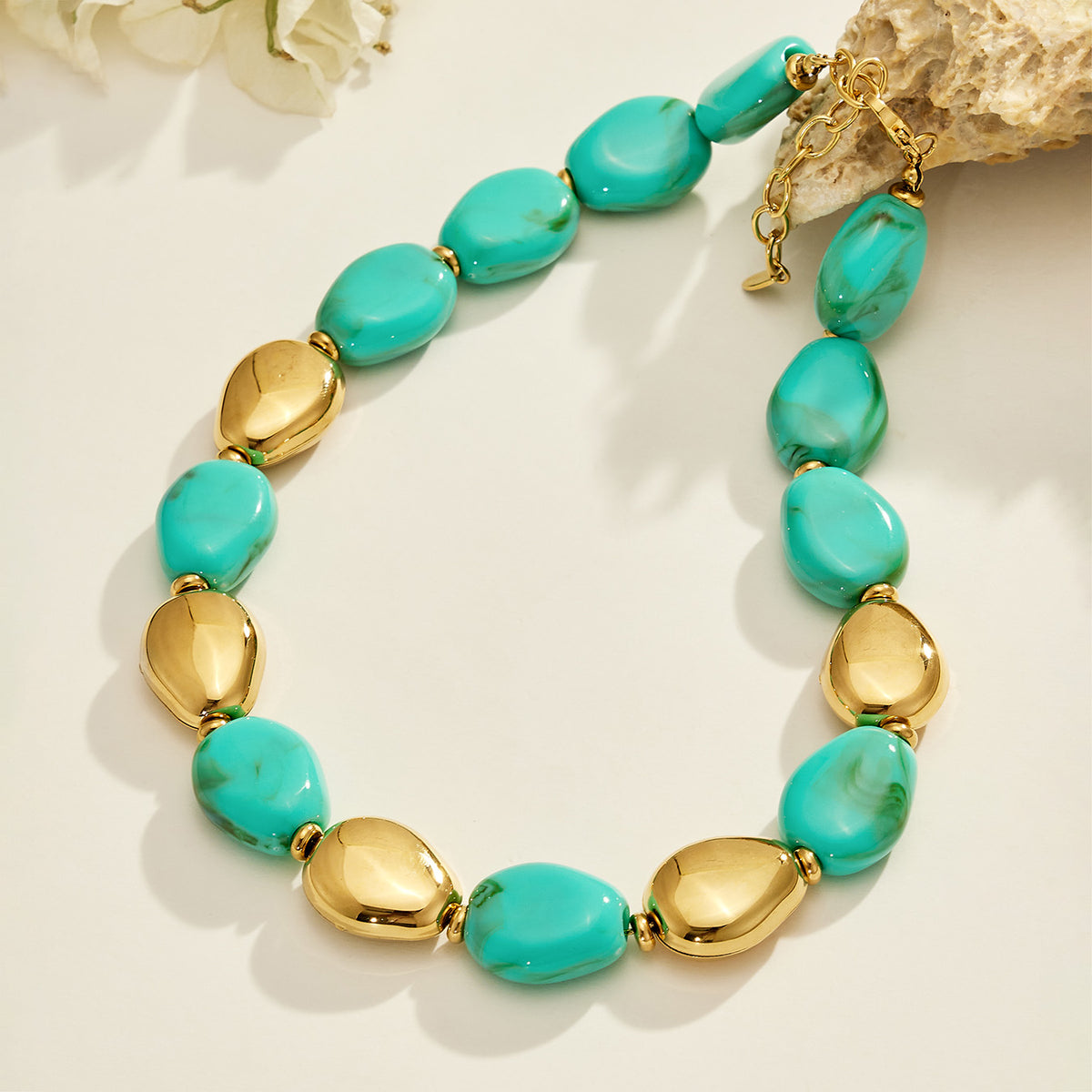 Green oval resin bead necklace with polished gold-tone metal accents displayed on a light surface