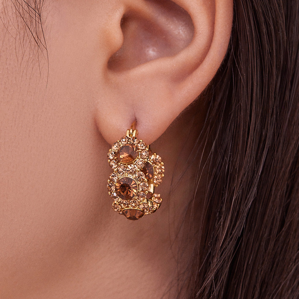 Close-up wearing view of U-shaped gold ear cuff earrings with zircon accents