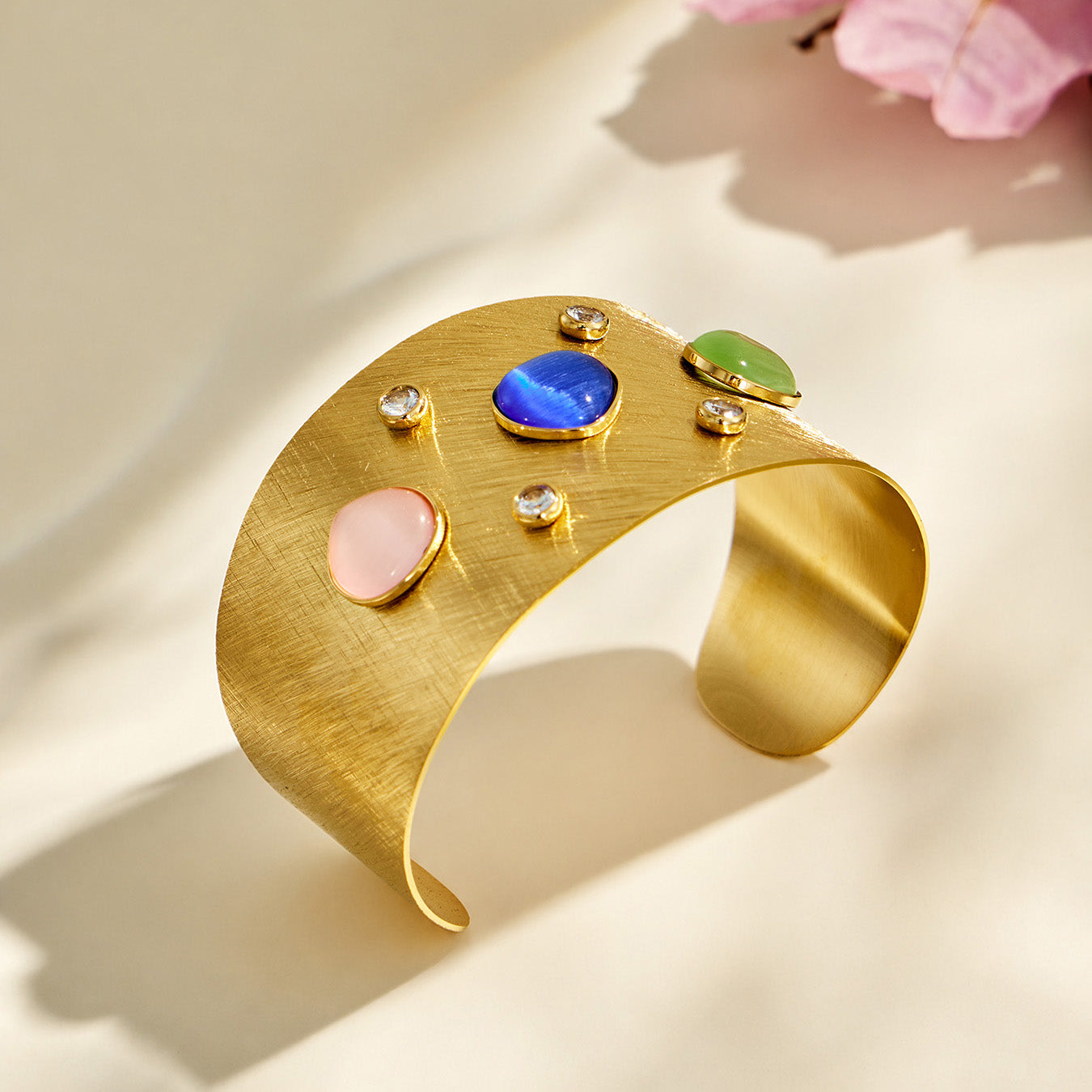 Wide gold cat-eye effect cuff bracelet displayed in a three-quarter flat-lay view