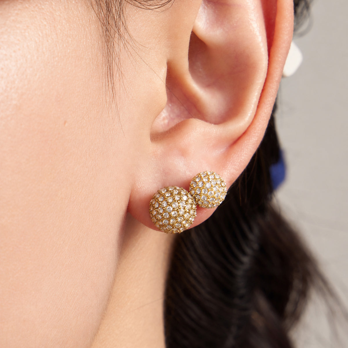 Gold zircon ball stud earring worn on ear with pavé stone detail