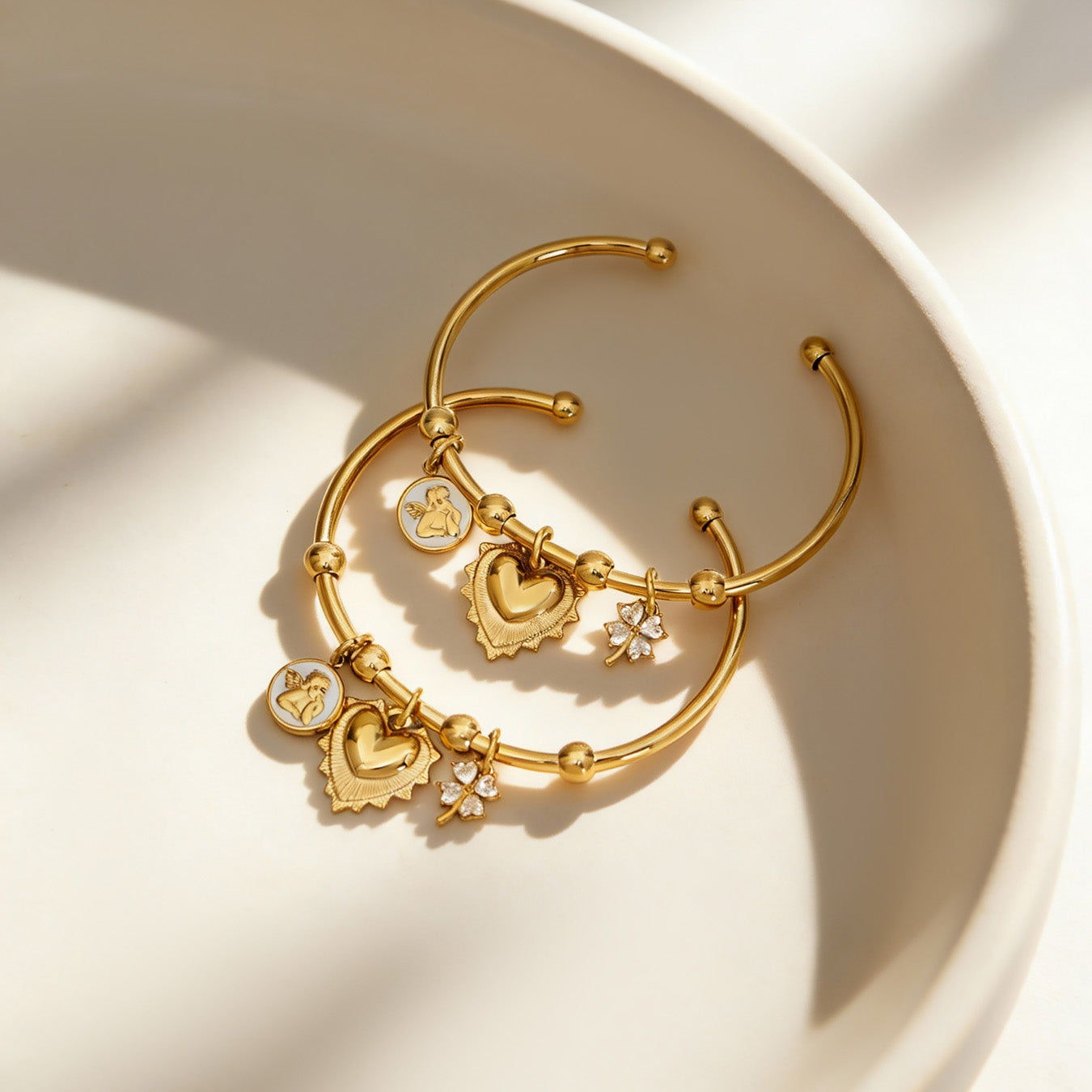 18k gold c-shaped pendant stainless steel bracelets displayed in bowl, elegant fashion style