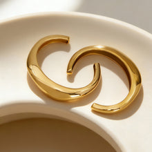 18k gold c-shaped polished stainless steel bracelets displayed in bowl, sleek fashion accessory