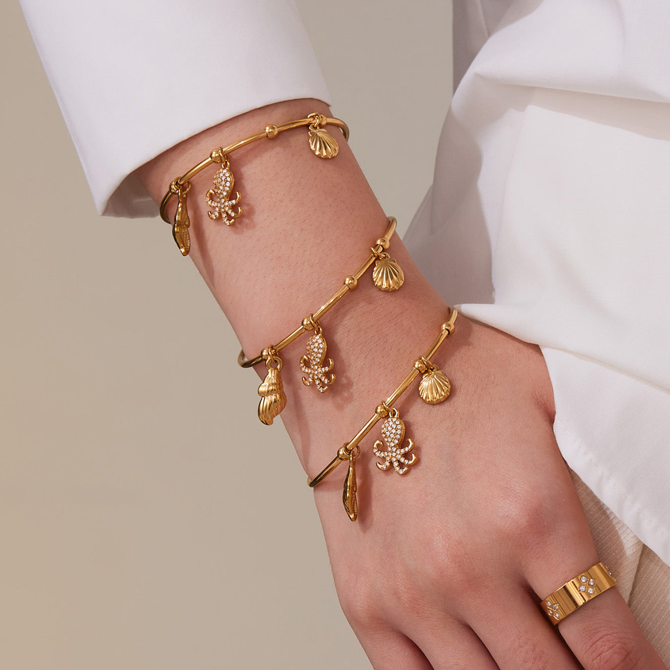 Model wearing stacked 18K gold ocean shell/octopus bangle set, beach style jewelry