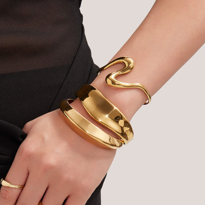 Closeup of 18k gold plated bold curved open bangle set on wrist, fashion statement design