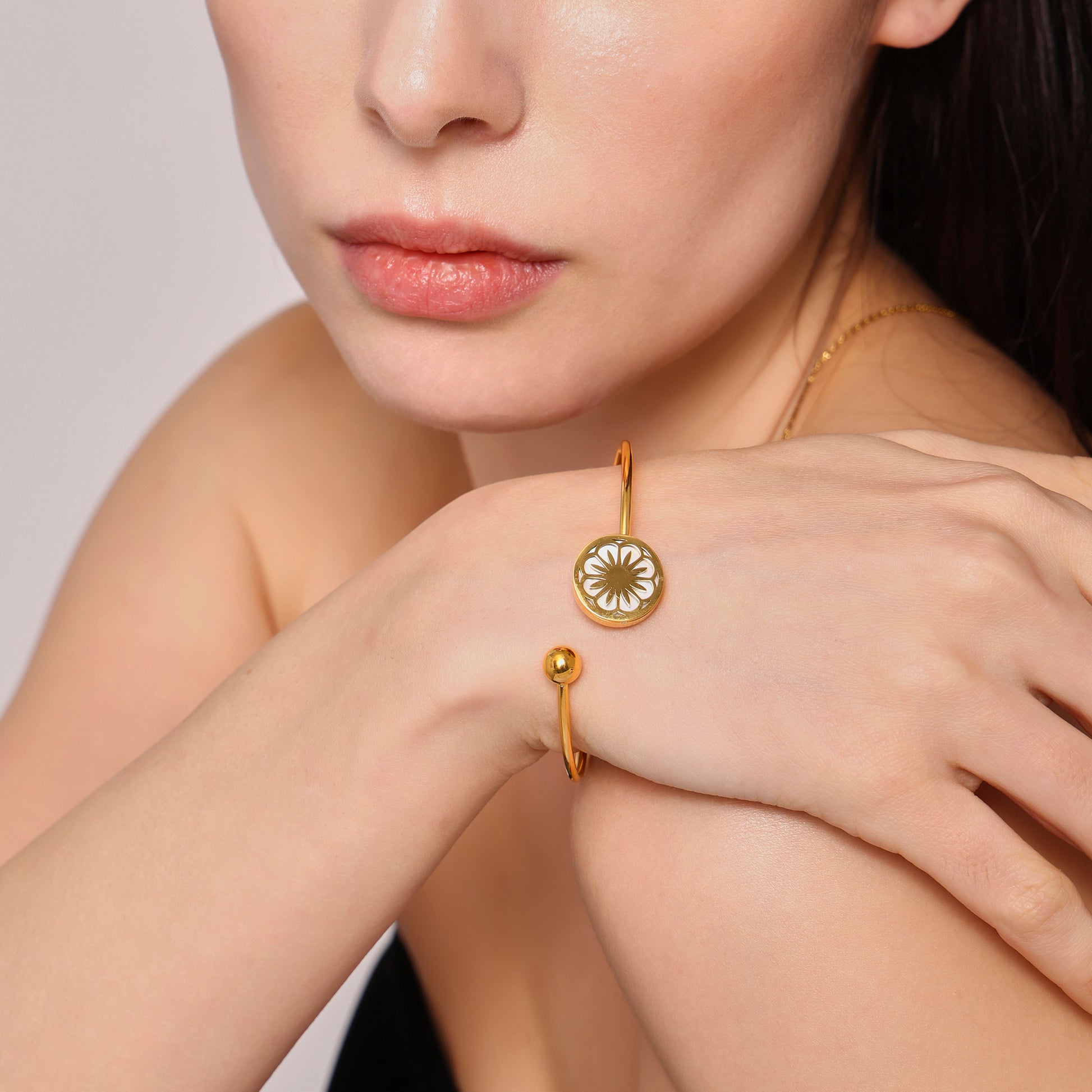 Closeup of 18k gold plated daisy sea shell stretch bangle on hand