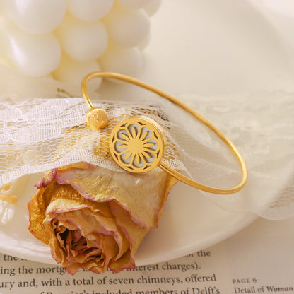 18k gold plated daisy sea shell stretch bangle displayed on floral scene
