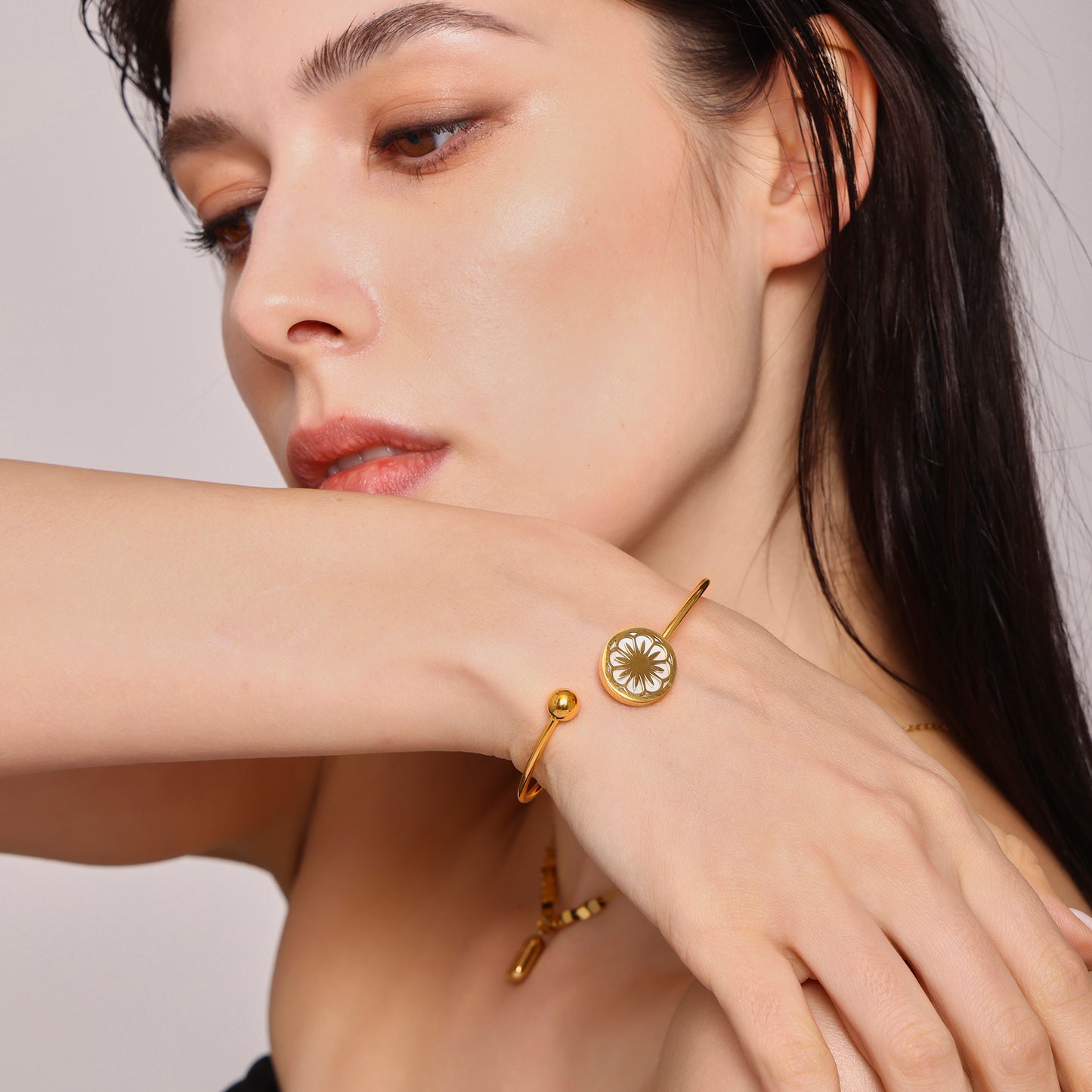 Side view of 18k gold plated daisy sea shell stretch bangle on wrist