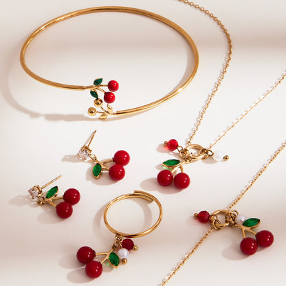 Closeup of 18k gold plated enamel red cherry jewelry set: necklace earrings bangle