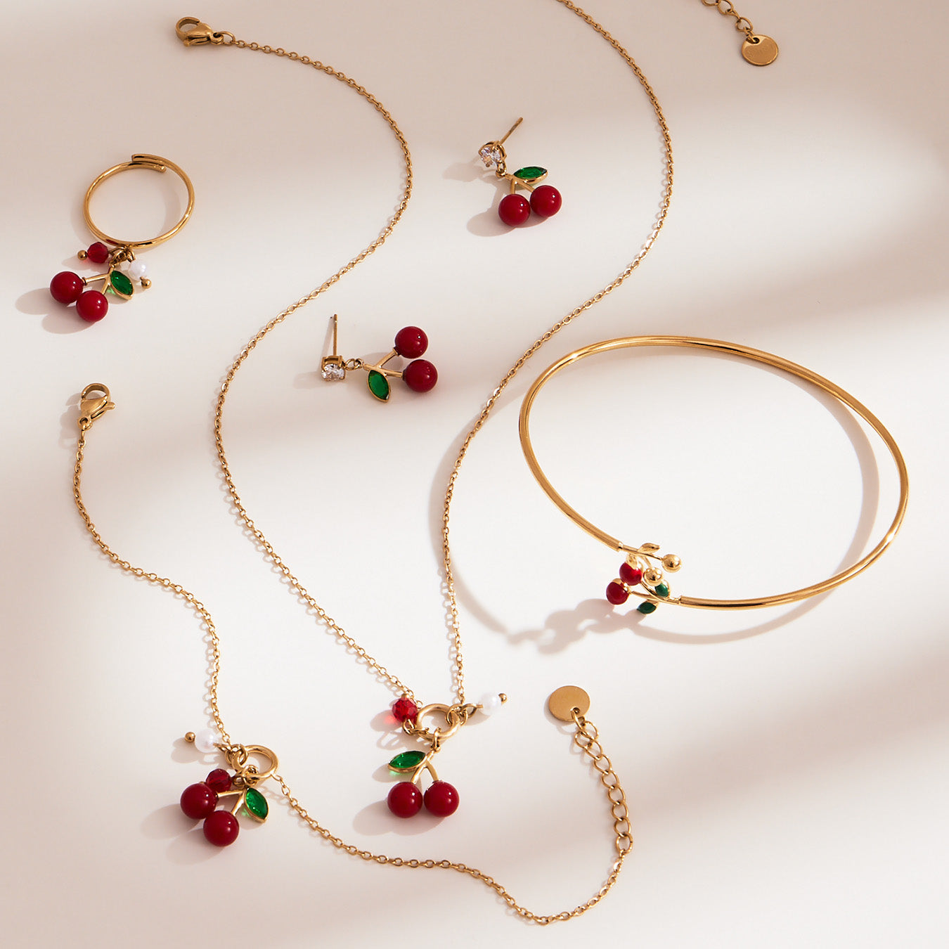 Gold 18k gold plated enamel red cherry jewelry set display on light background
