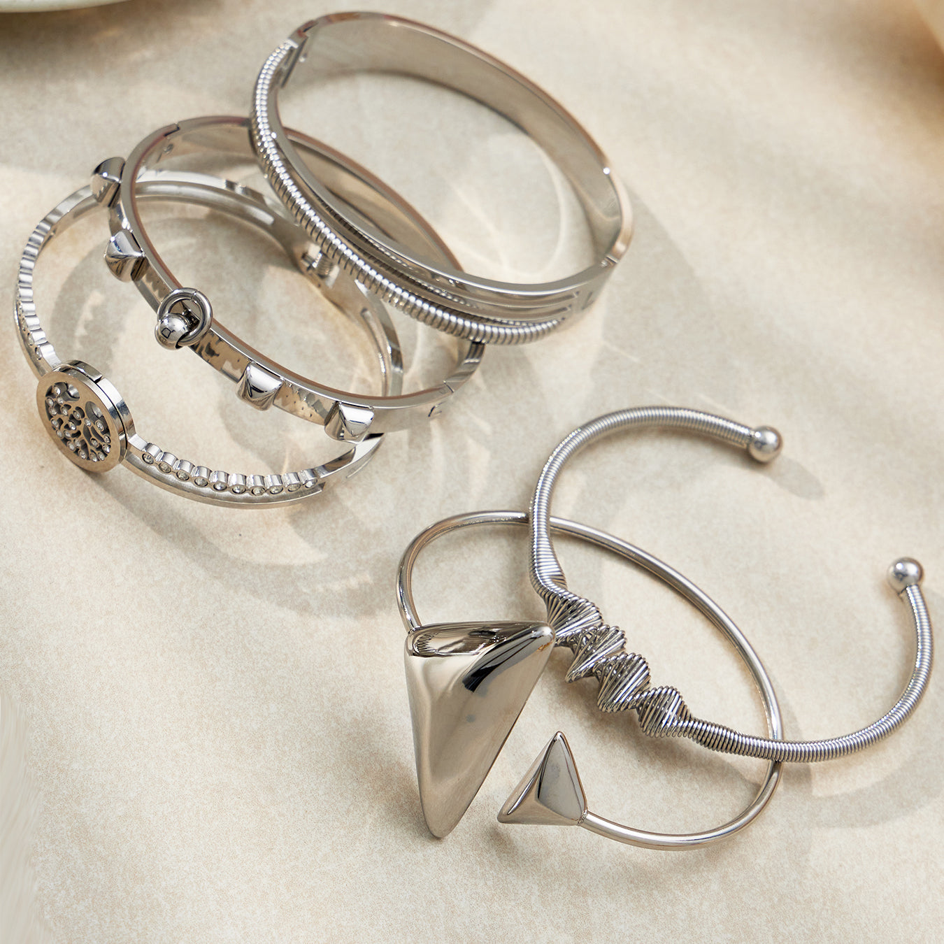 Silver 18k gold plated geometric open bangle set, stacked on light background