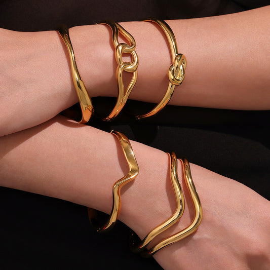 Multiple 18k gold plated knot twist bangle set on wrists, gold stacked cuff bracelet
