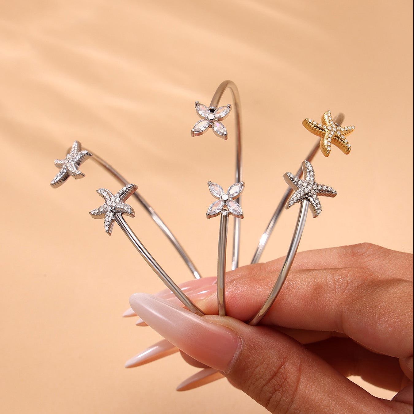 Hand holding silver 18k gold plated ocean 5A zircon bangle set: fish starfish design