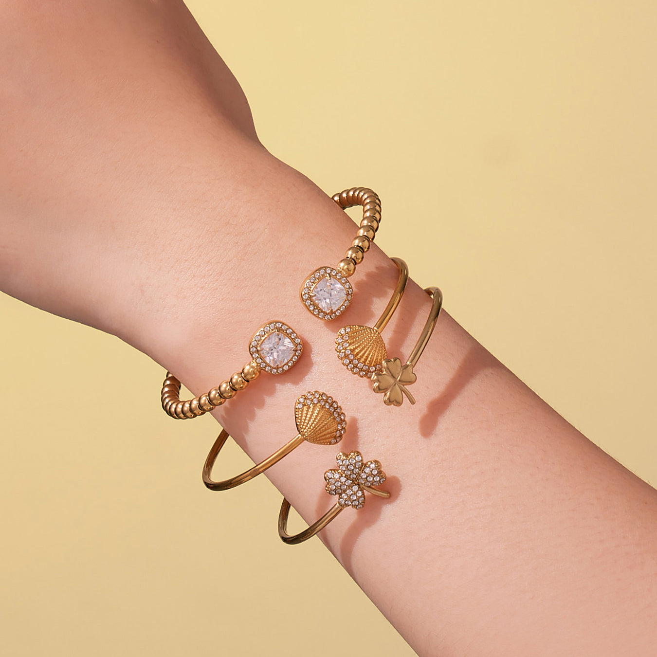 model wearing 18k gold shell clover stone cuff bracelets, stacked layered look, elegant fashion style