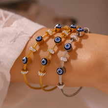 Woman wearing 18K gold & silver titanium steel evil eye enamel bracelets with rhinestones